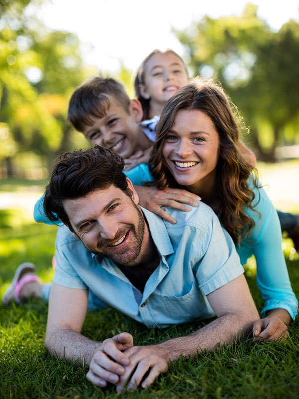Smiling family lying on grass enjoying time together after orthodontic care at SS Orthodontics in Glendale and Phoenix, AZ