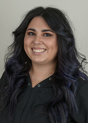 Staff photo of Alexis with wavy dark hair and blue highlights smiling at SS Orthodontics in Glendale and Phoenix, AZ