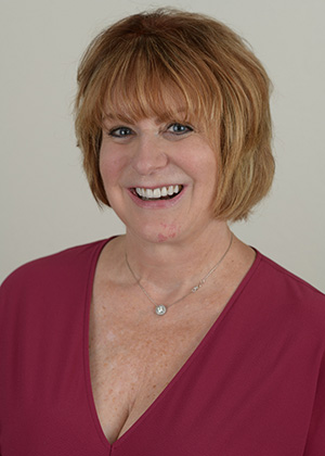 Staff photo of Jan with short auburn hair in a burgundy top smiling at SS Orthodontics in Glendale and Phoenix, AZ