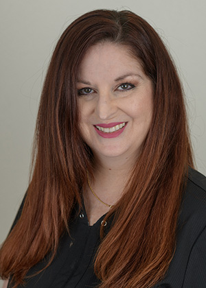 Staff photo of Sherry with straight auburn hair in a black top smiling at SS Orthodontics in Glendale and Phoenix, AZ
